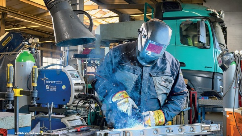Ein Schweißer in einem Vollmontur-Schutzanzug, der in einer Fabrik tätig ist.